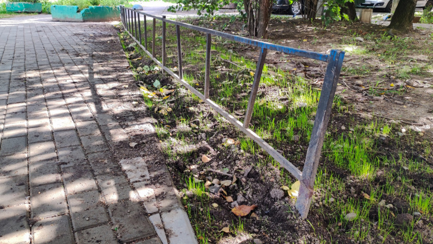 Низкий металлический заборчик отделяет клумбу от тротуара, а из земли уже пробивается трава
