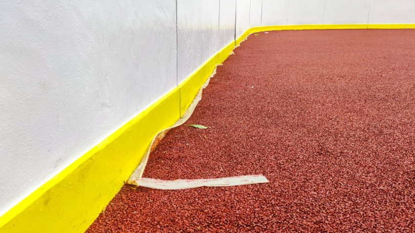 Строительная лента на резиновом покрытии у борта спортивной площадки