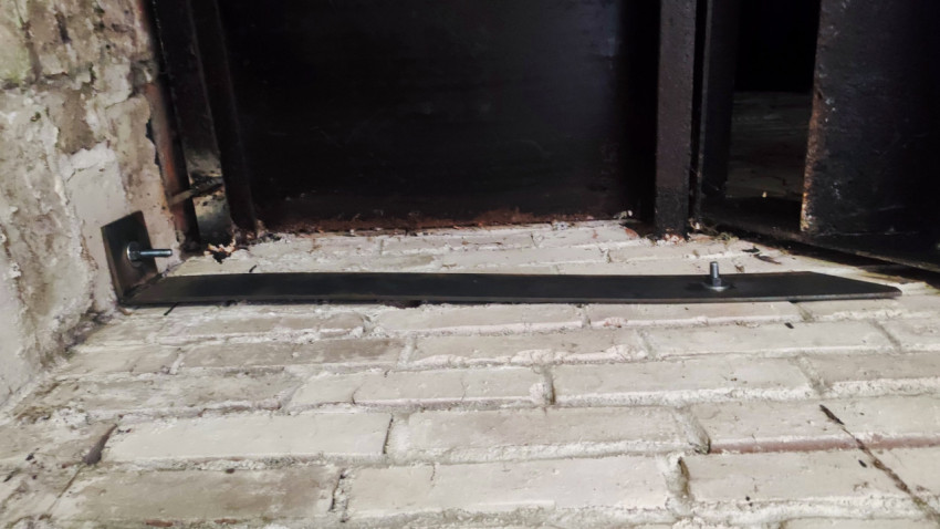 Ржавый металлический порог и нижняя часть двери с крепежом на кирпичном основании