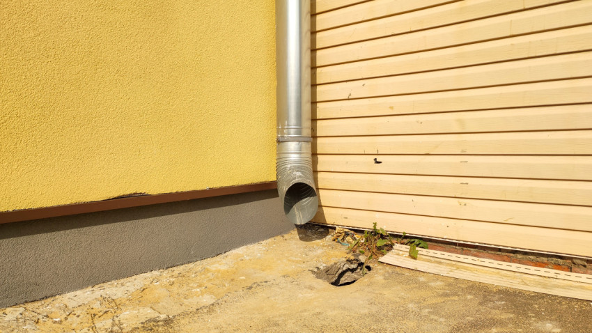 Нижняя часть фасада с водосточной трубой и трещинами отмостки