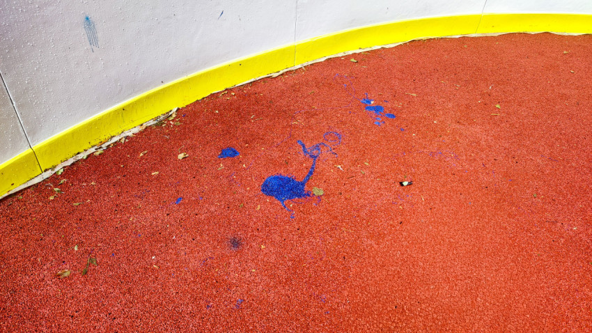 Большое пятно синей краски на красном резиновом покрытии