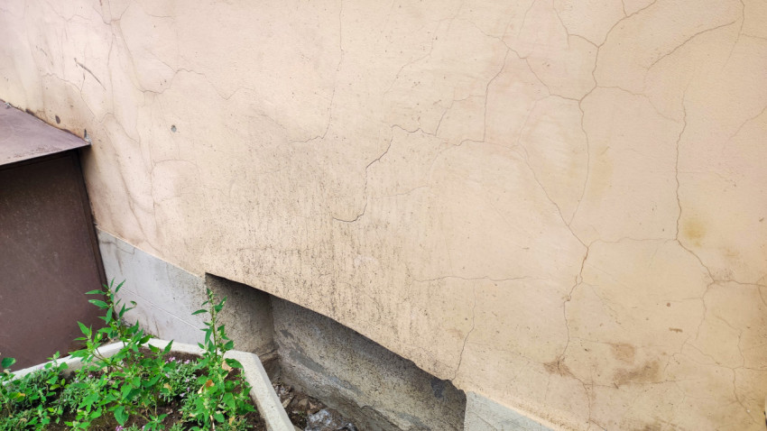 Крупный план трещин и загрязнений на штукатурке фасада здания