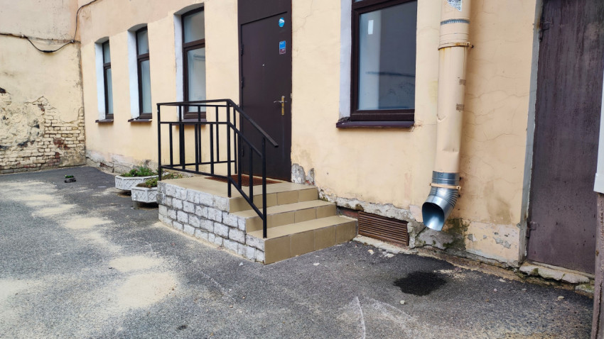 Вход в подъезд с бетонными ступенями, перилами, дверью и элементами цоколя у жилого дома