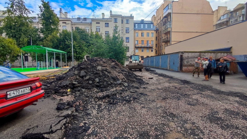 Двор с кучами снятого асфальта и техникой во время дорожных работ