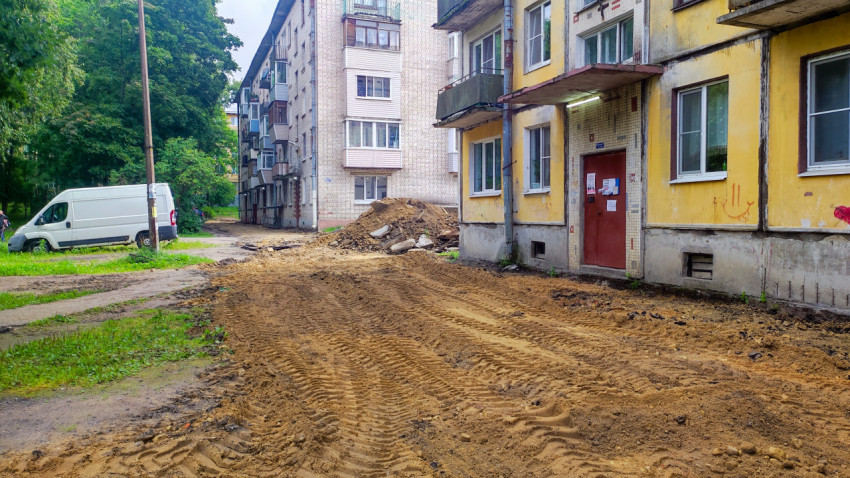Подъезд жилого дома рядом с зоной раскопок и временным грунтовым покрытием