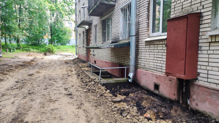 Раскопанный участок у цоколя дома с входом в подвал и водостоком