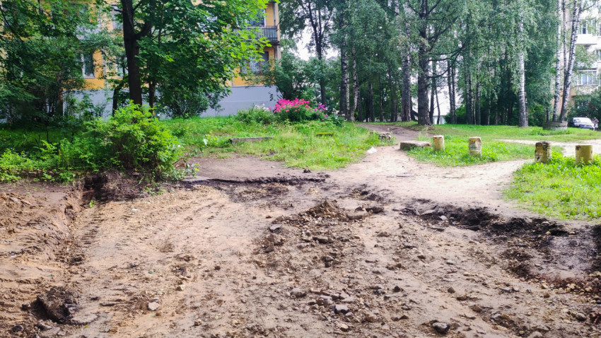 Разрытый грунт и колея техники на зелёной дворовой территории