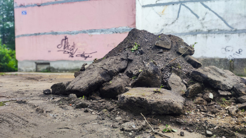 Куча снятого асфальта и щебня у стены дома после дорожных работ