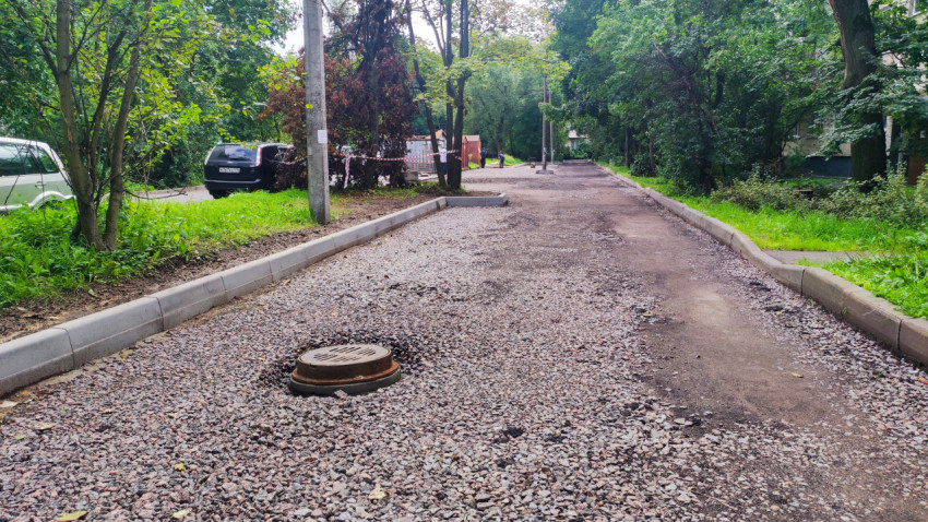 Дворовой проезд со щебнем, бордюрами и люком во время дорожного ремонта