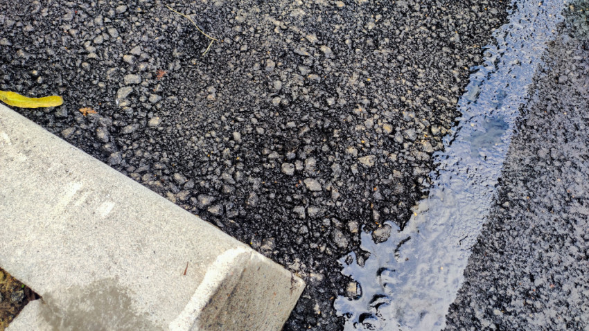 Битумная мастика на стыке асфальта у бордюра, крупный план