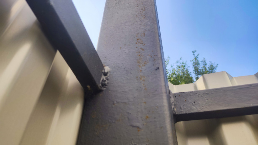 Нижний ракурс металлической стойки и поперечин каркаса ограждения на фоне неба