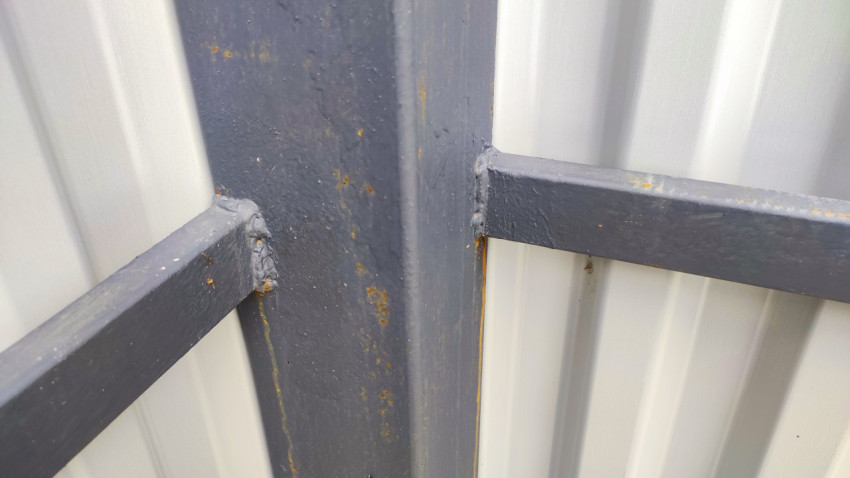 Сварной шов и крепление металлического профиля на каркасе ограждения из профнастила