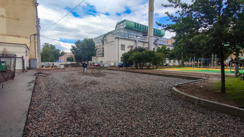Широкий двор с деревьями, детской площадкой и хозяйственными зданиями на заднем плане