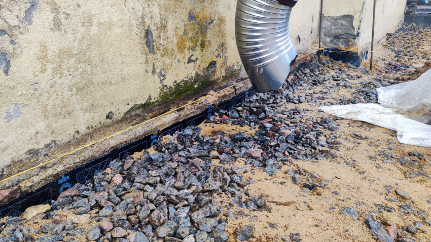 Подключение водостока к гофрированной трубе с засыпкой щебнем у стены здания