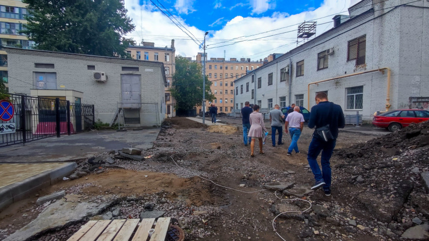 Разрытый дворовой проезд с гравием, коммуникациями и людьми на участке ремонта