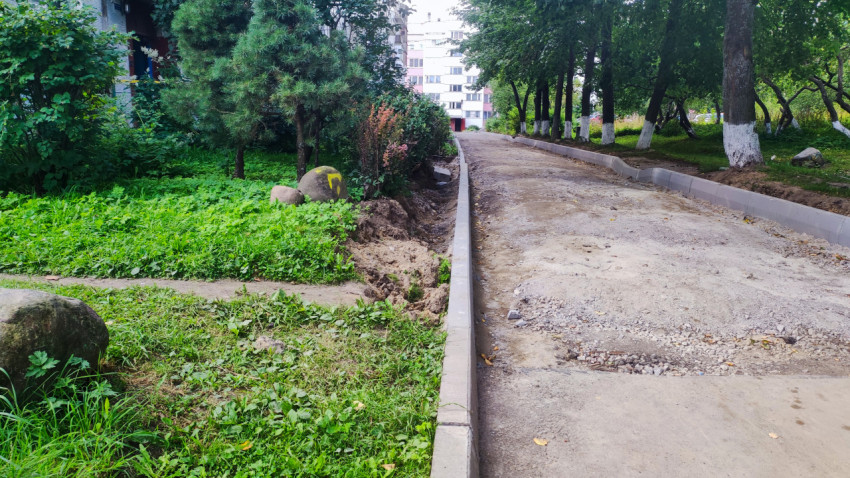 Щебёночный дворовый проезд с бордюрами вдоль зелёной зоны и деревьев