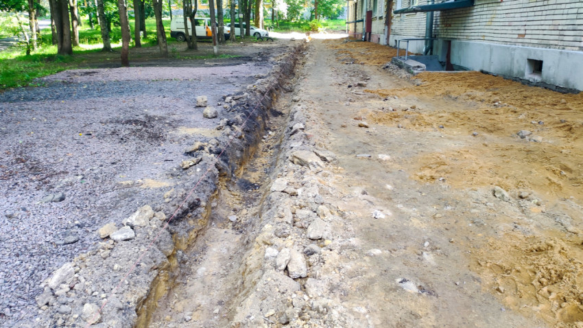 Участок двора с траншеей, кучами щебня и песка на этапе подготовки под новое покрытие