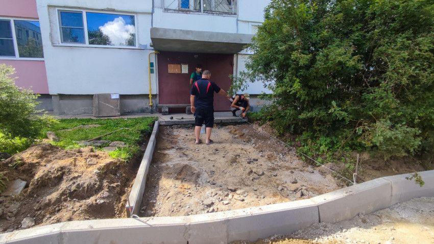 Подготовка основания и установка бордюров у подъезда жилого дома с разметочной нитью