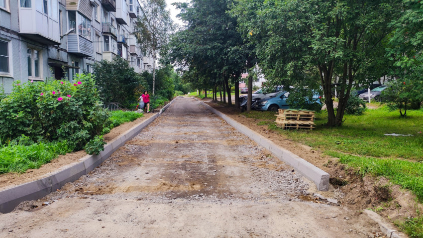 Новый бордюр вдоль дворовой дорожки у панельного дома, подготовленной под укладку покрытия