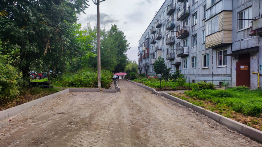 Дворовой проезд с новыми бордюрами вдоль панельного дома и опорой освещения на этапе реконструкции