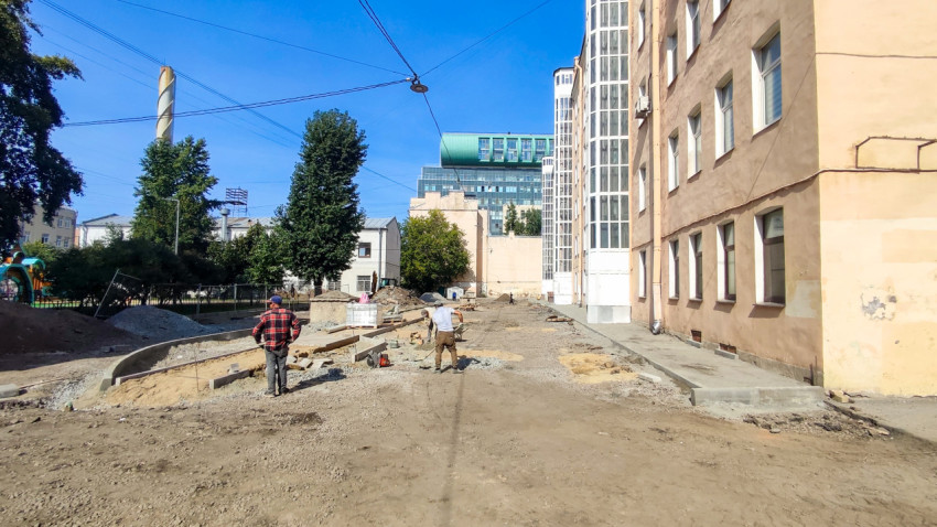 Реконструкция двора: рабочие, разрытый грунт, бордюры и строительные материалы между жилыми домами