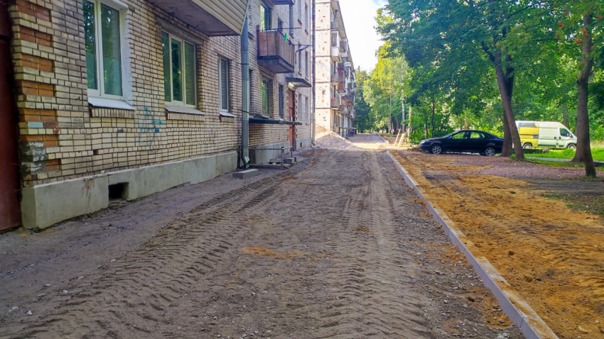 Дворовой проезд вдоль кирпичного дома с щебёночным основанием и линией установленных бордюров