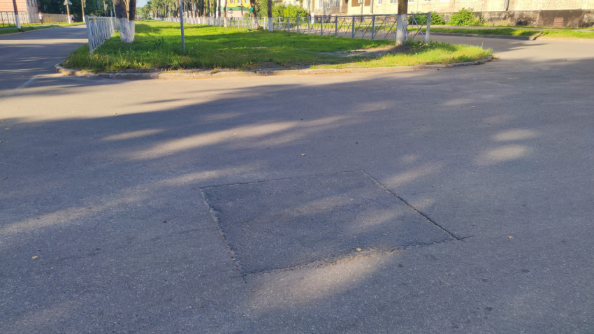 Квадратная заплатка на асфальте выделяется тёмным пятном среди старого дорожного покрытия