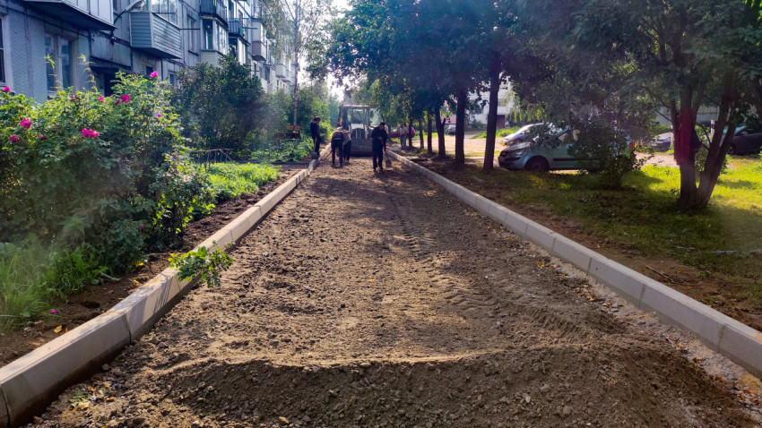 Рабочие готовят дворовой проезд: щебень и грунт выравнивают между новыми бордюрами
