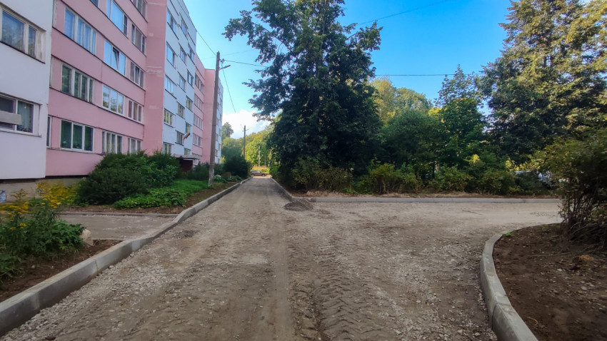 Грунтовый проезд у розового дома подготовили под асфальт: стоят бордюры и виден след техники