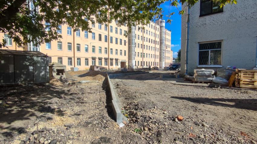 Разметка будущей дорожки бордюром на гравийной площадке у многоэтажек