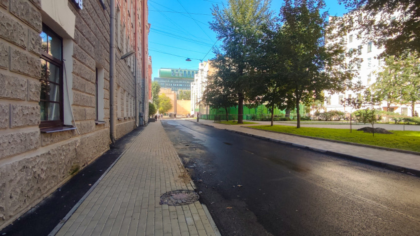 Свежий асфальт и новый тротуар на улице с контактными проводами