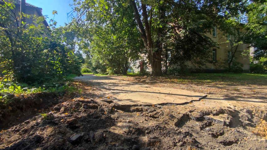 Разрушенная пешеходная дорожка с разрытым грунтом во дворе