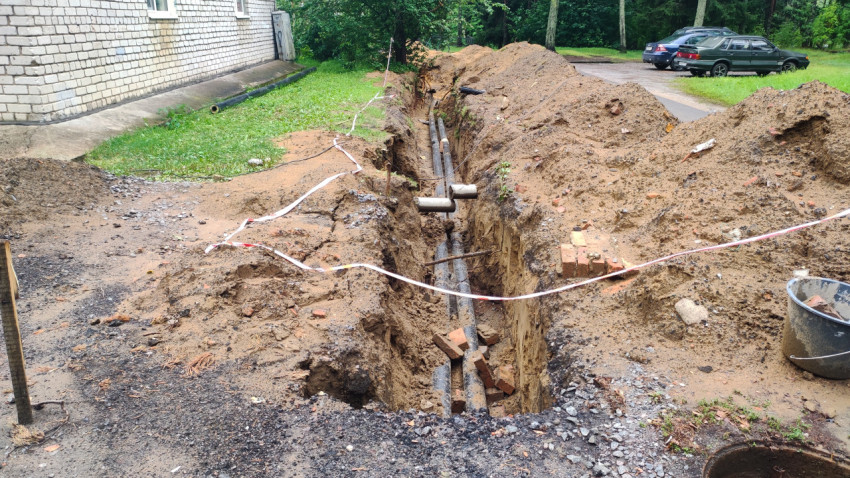 Траншея с уложенными трубами у жилого дома