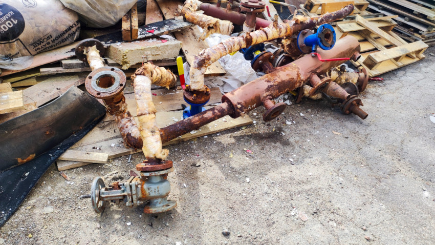 Демонтированные ржавые трубы с фланцами и вентилями на площадке ремонта инженерных коммуникаций