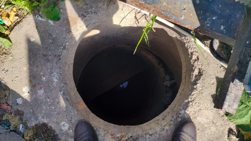 Открытый бетонный колодец с водой на дне во дворе, снятый крупным планом сверху