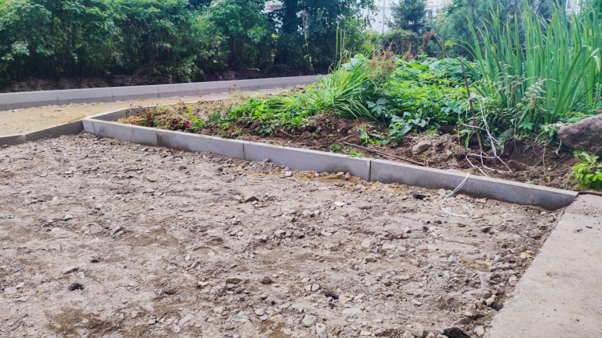 Клумба с цветами и новая линия бордюров на участке благоустройства во дворе