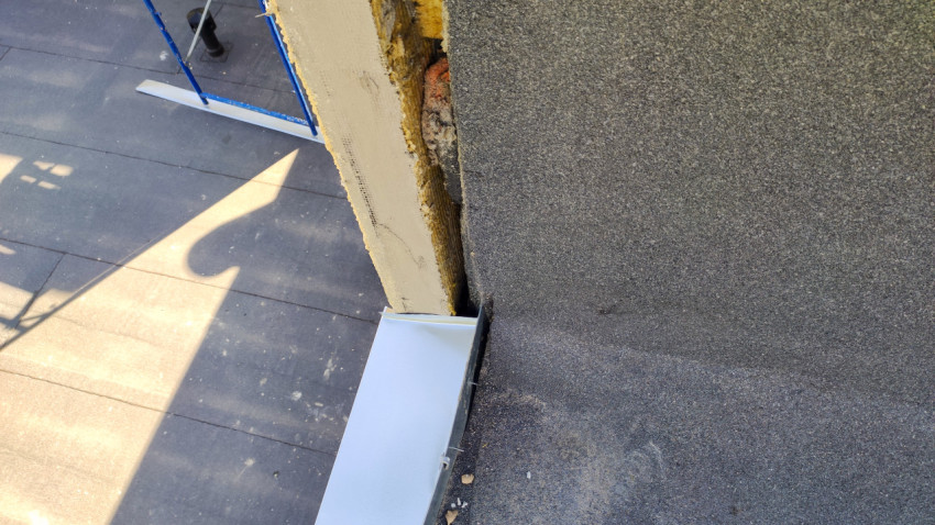 Повреждённый край кровли с открытым утеплителем и металлическим отливом