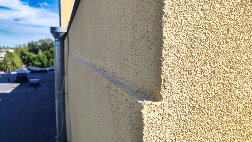 Фасадный угол здания с водосточной трубой и карнизным выступом