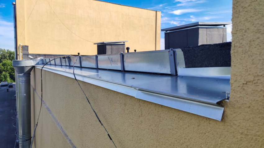 Водосточная воронка и металлический парапетный колпак на плоской крыше