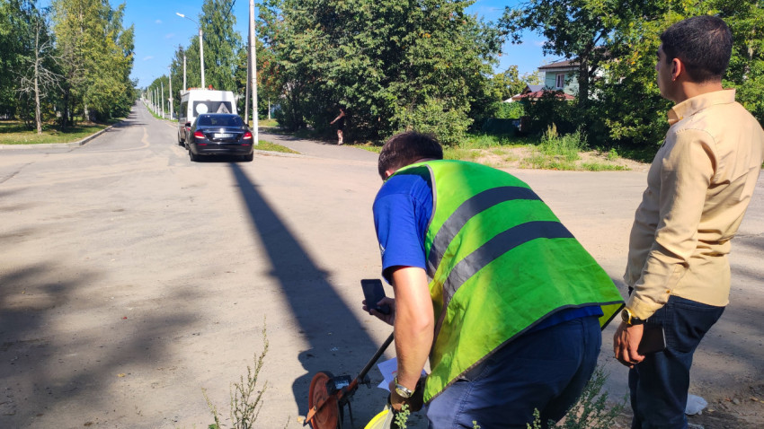 Сотрудник с измерительным колесом делает замер на дороге рядом с фургоном дорожной лаборатории