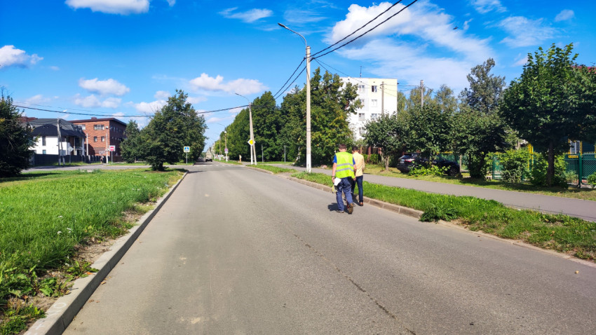 Широкая улица с фонарями и проводами, по которой вдали идут дорожные измерители