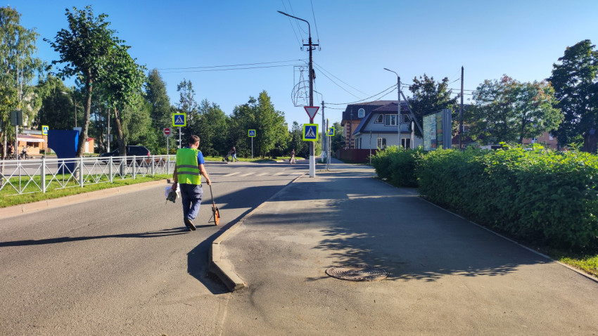 Рабочий с измерительным колесом идёт к перекрёстку с «зеброй» и знаками перехода