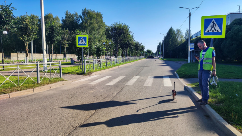 Пешеходный переход со знаками и «зеброй», рядом рабочий и измерительное колесо у бордюра