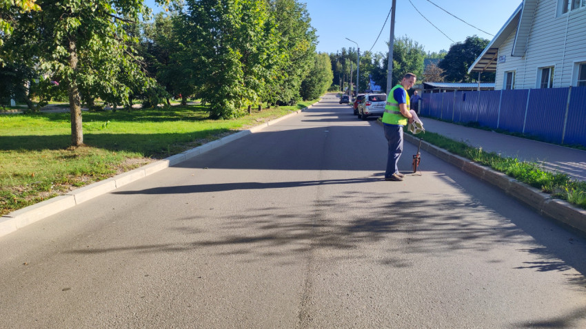 Мужчина с мерным колесом измеряет участок дороги у частных домов