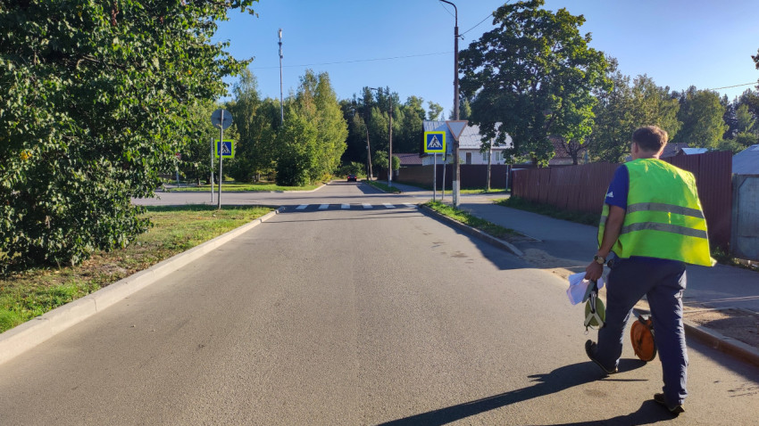 Специалист с мерным колесом работает у пешеходного перехода на дороге