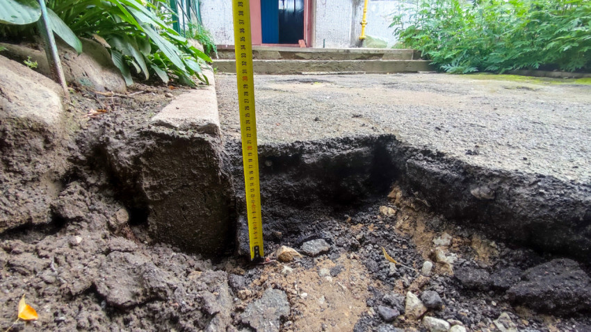 Замер глубины ямы рулеткой у края асфальтового покрытия