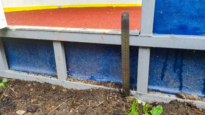 Контроль просвета под ограждением спортплощадки металлической линейкой