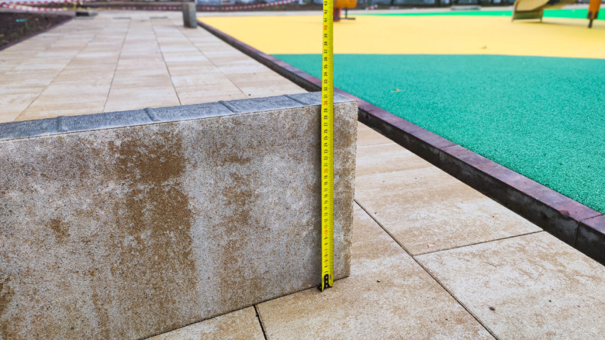 Контроль высоты бордюра рулеткой у резинового покрытия площадки