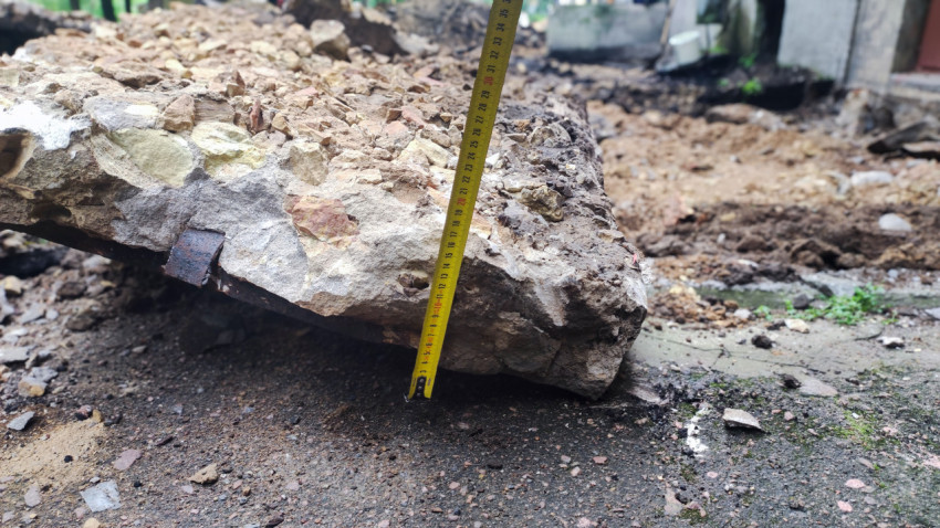 Рулетка измеряет перепад на куске разрушенного асфальта