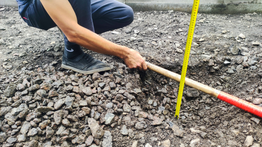 Контроль глубины слоя основания у бордюра рулеткой во время ремонта дворового проезда